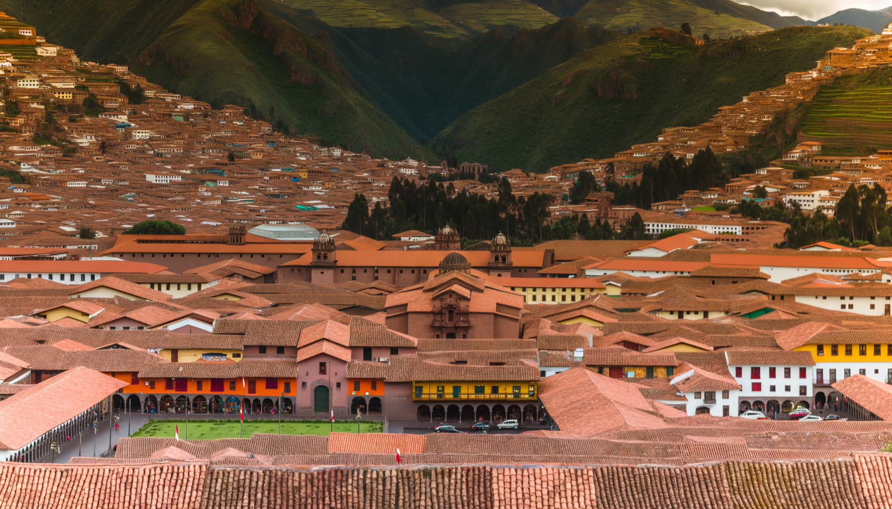 Orange rooftops of Cusco against green mountains
